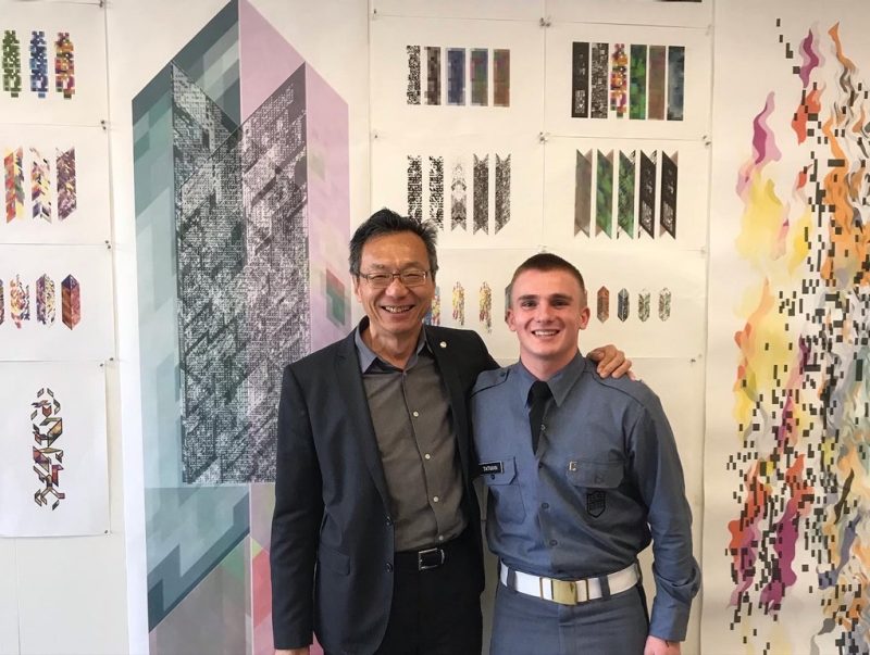 Dean Liu and a student smile together in front of project