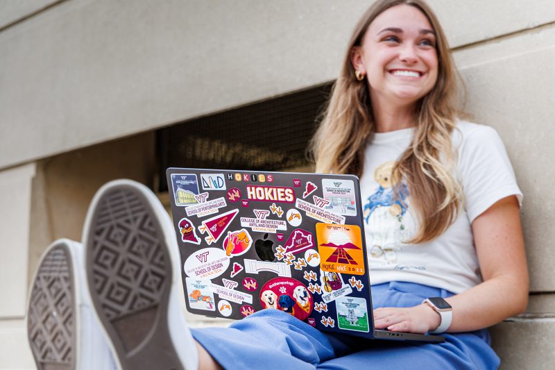 Student sitting working on a laptop covered in stickers