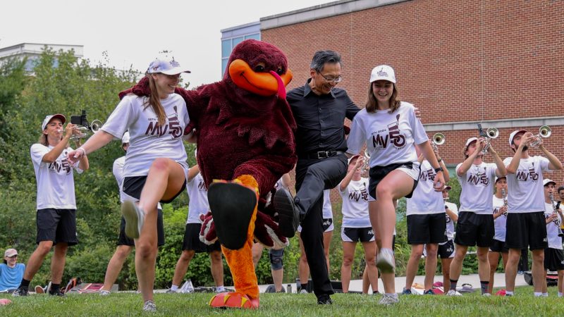 Dean Liu doing a high kick with the Marching Virginians during the Hokie Pokie outside at welcome picnic