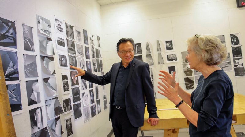 Dean Liu and a faculty member discussing work pinned on the wall