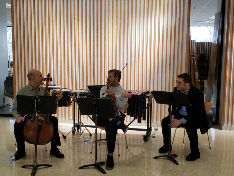 Three music professors sitting and playing in Cowgill Hall lobby