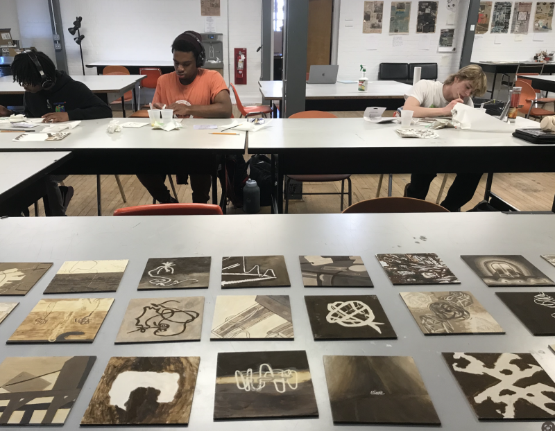 Student work in the foreground and students working in the background.