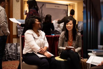 Two people laugh while sitting at a job fair.