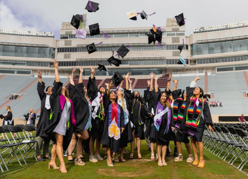 A group of graduating students tossing their caps into the air at a commencement ceremony in Lane Stadium.