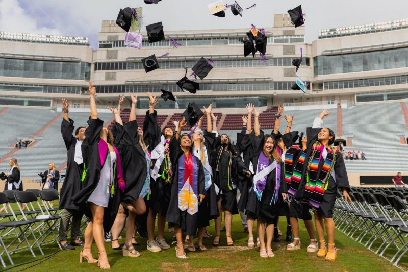 Students throwing graduation caps in the air in Lane Stadium