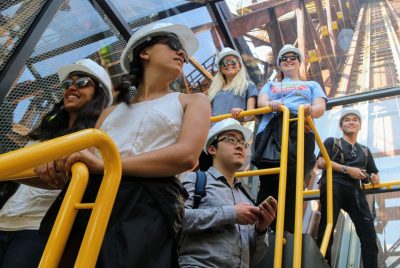 Students wearing hard hats examine a structure while on a study abroad trip.