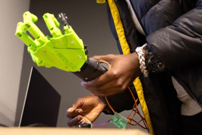 Hands holding robotic arm and wires.