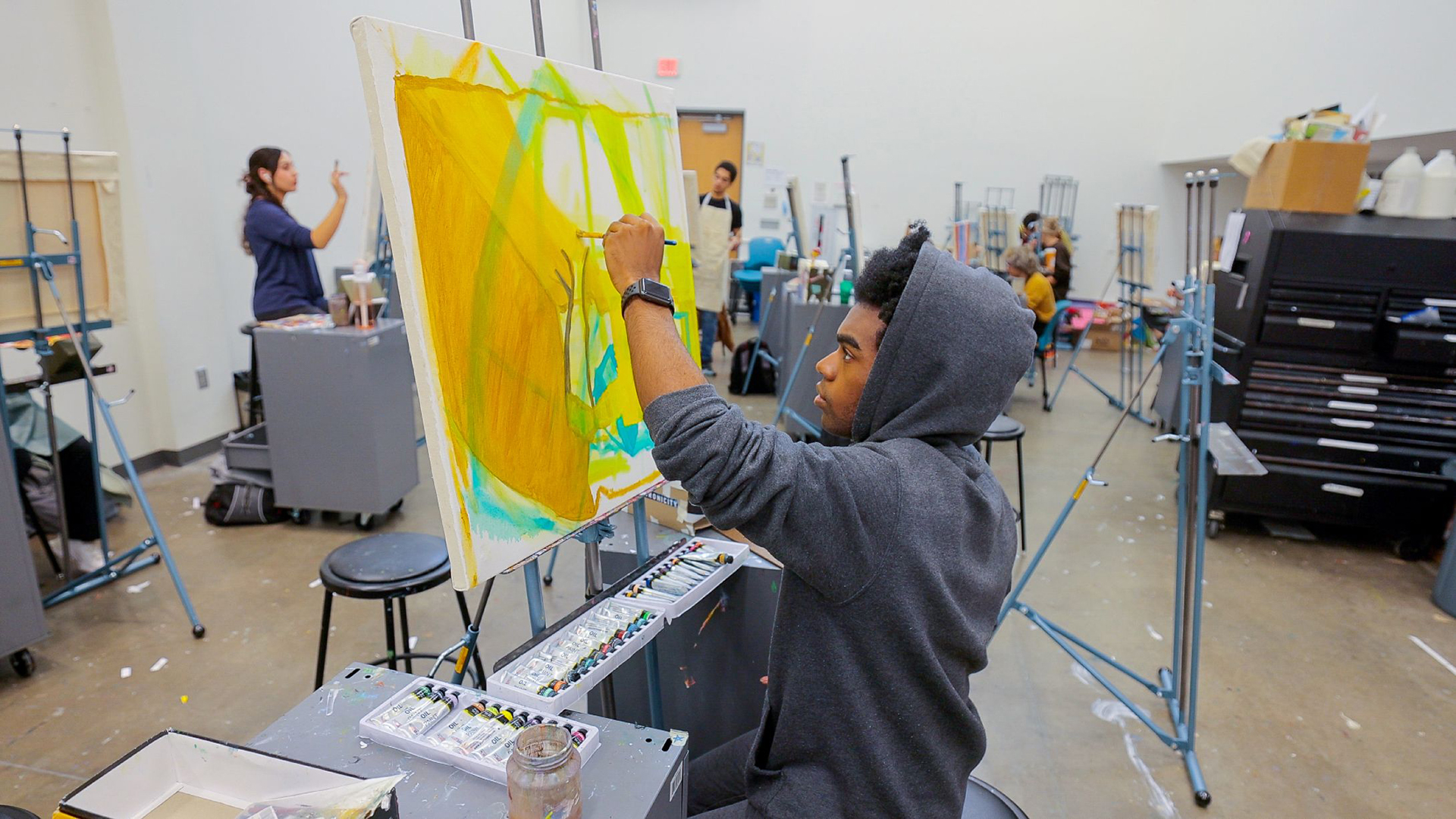 Student painting on a canvas in class.