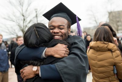 Cap and Gown Graduate Student Hug and Smile
