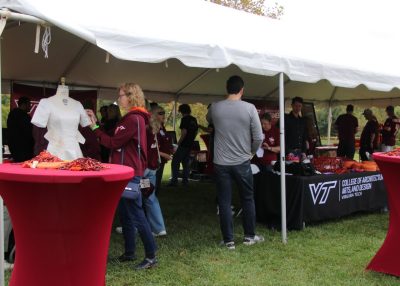 Tent with people under it interacting with activities at tailgate.