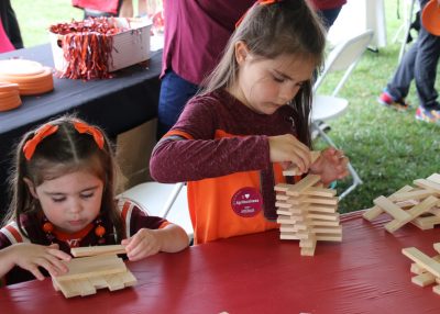 Two children play with building blocks at tailgate.