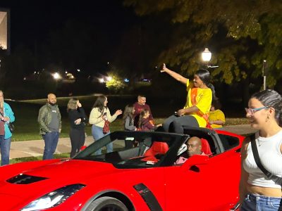 Kayla Renee Scott, nominated for Homecoming Court, waves from a red car during Homecoming parade.