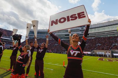 Cheerleader holding up sign that says, "NOISE" at the Homecoming game against Wake Forest.