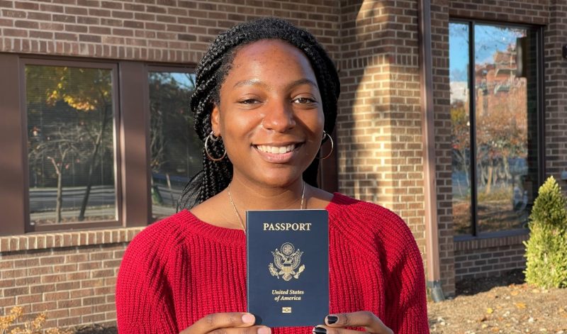 Aryn Lovell standing outside of the Global Education Office with a U.S. passport book