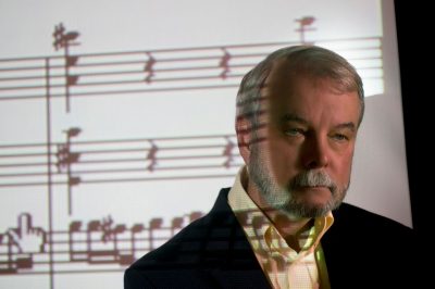 James Sochinski with musical notes dispalyed on a screen behind him.