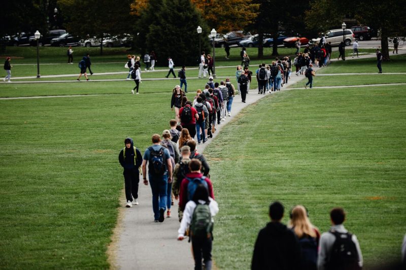 A sidewalk crossing the Drillfield is filled with students,